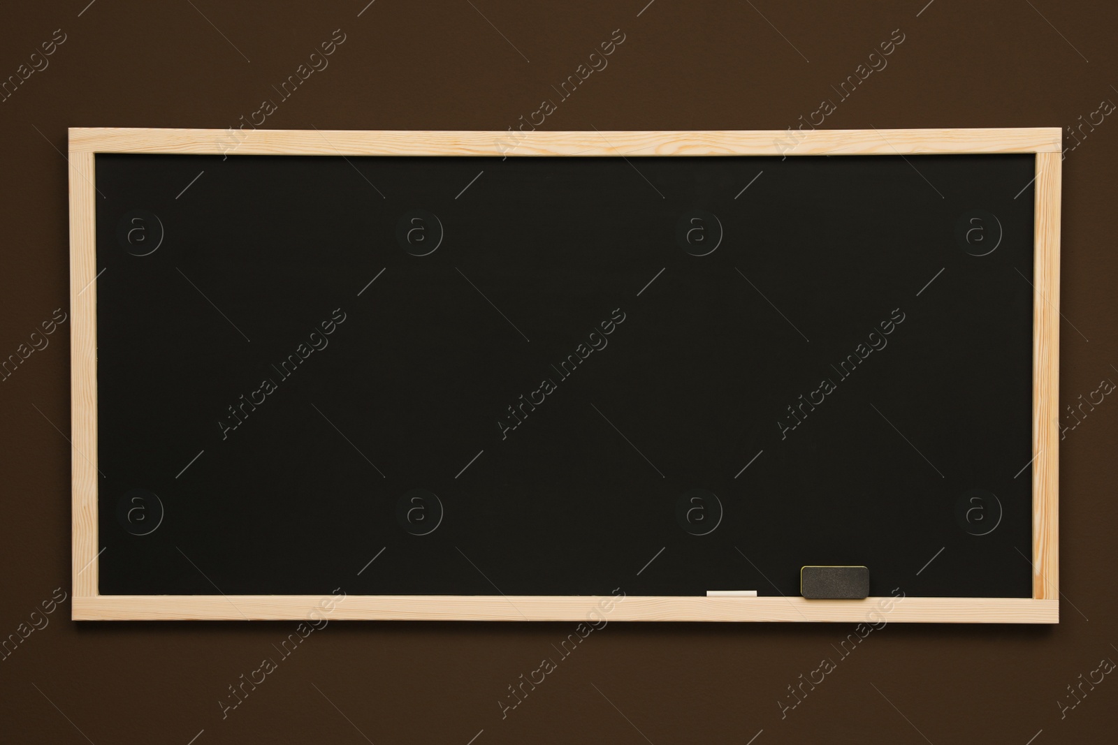Photo of Clean black chalkboard hanging on brown wall