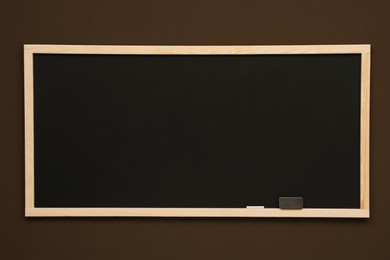 Clean black chalkboard hanging on brown wall