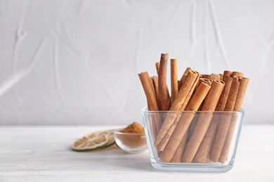 Photo of Bowl with aromatic cinnamon sticks on table