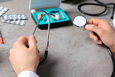 Photo of Doctor with stethoscope and different medical objects at table, closeup