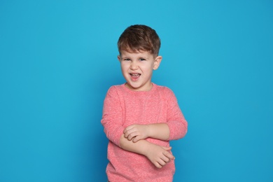 Photo of Little boy scratching arm on color background. Annoying itch