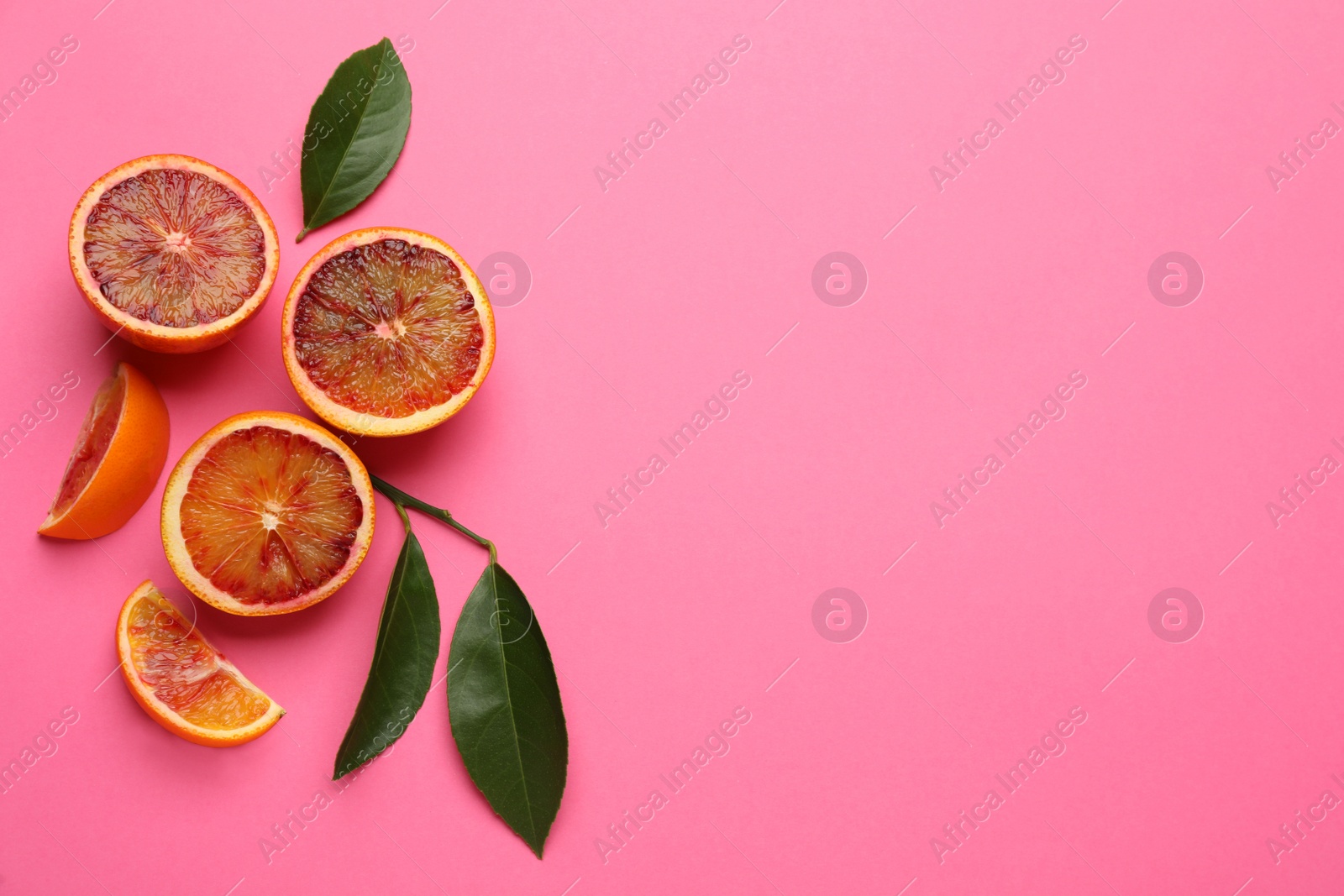 Photo of Ripe sicilian oranges and leaves on pink background, flat lay. Space for text