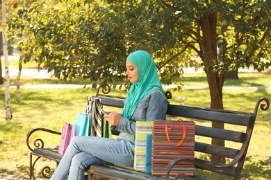 Photo of Muslim woman with mobile phone sitting on bench in park