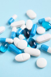 Photo of Many different pills on light blue background, closeup