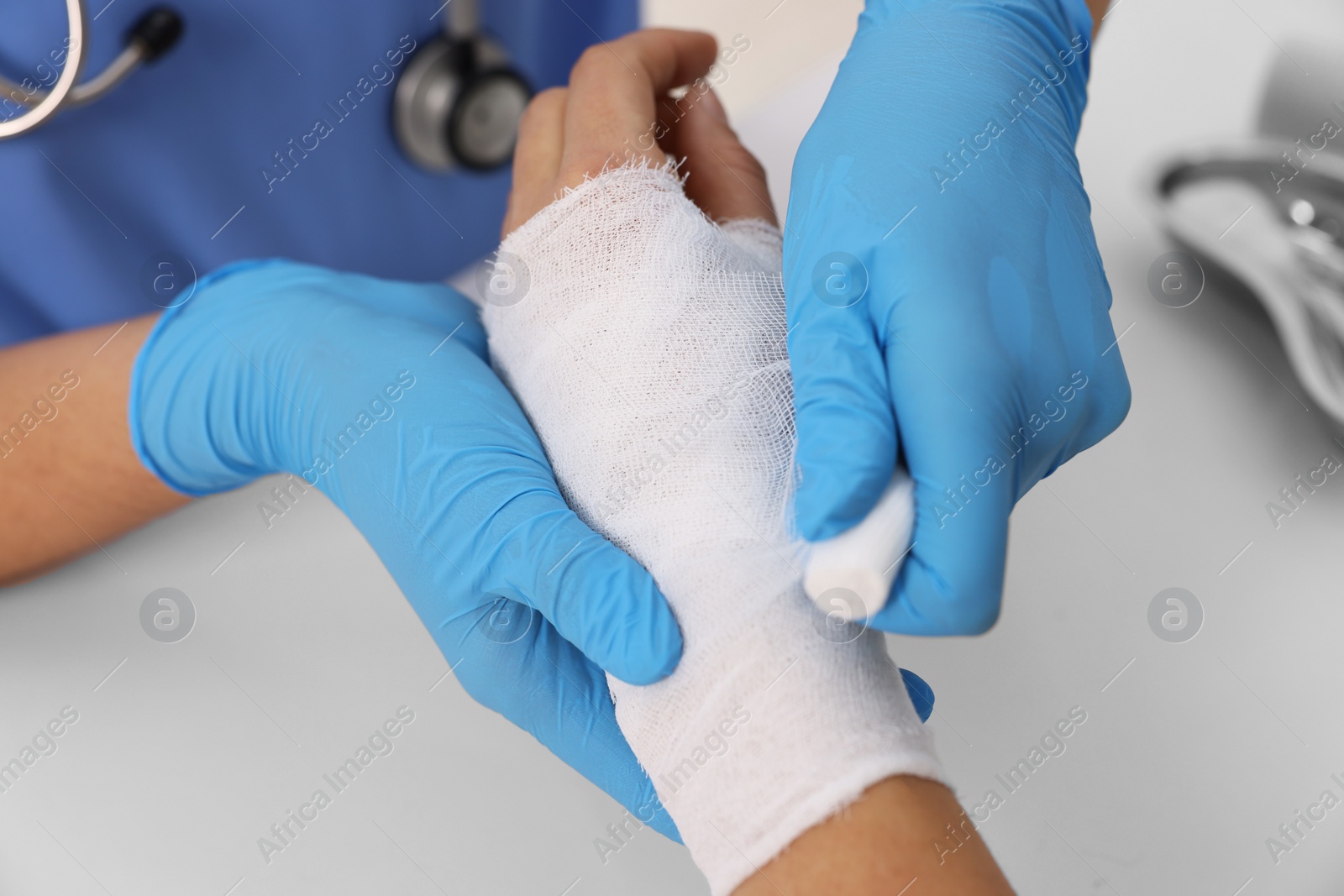 Photo of Doctor bandaging patient's burned hand at table, closeup