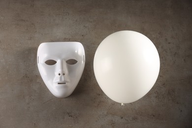 Photo of Theatrical performance. Plastic mask and white balloon on grey table, top view