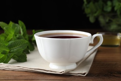 Cup of hot aromatic tea with mint on wooden table