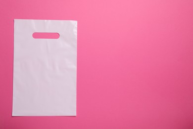 Photo of White plastic bag on bright pink background, top view. Space for text