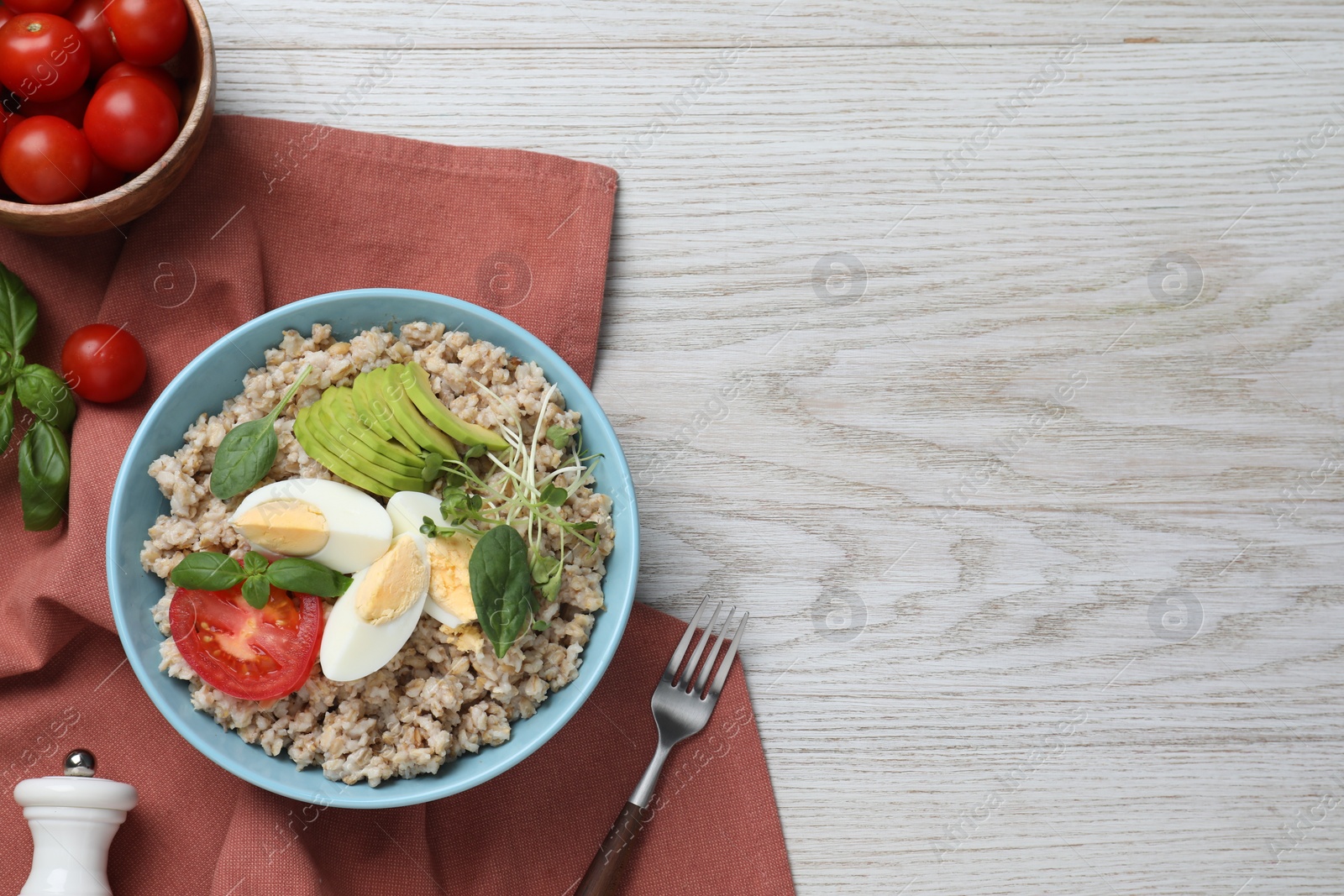 Photo of Delicious boiled oatmeal with egg, tomato and avocado served on light wooden table, flat lay. Space for text