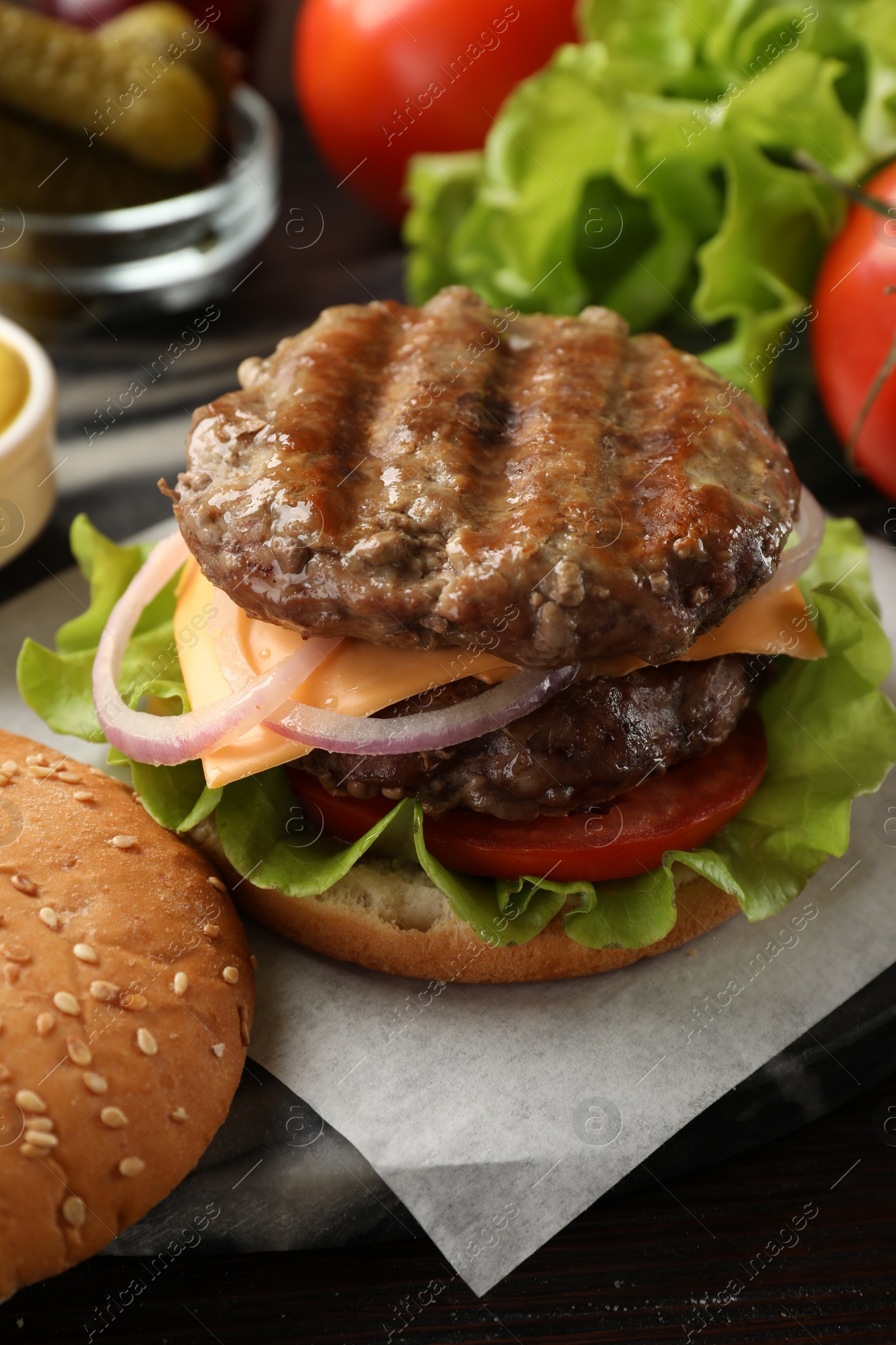 Photo of Tasty hamburger with patties, cheese and vegetables on wooden table