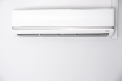 Modern air conditioner on white wall indoors