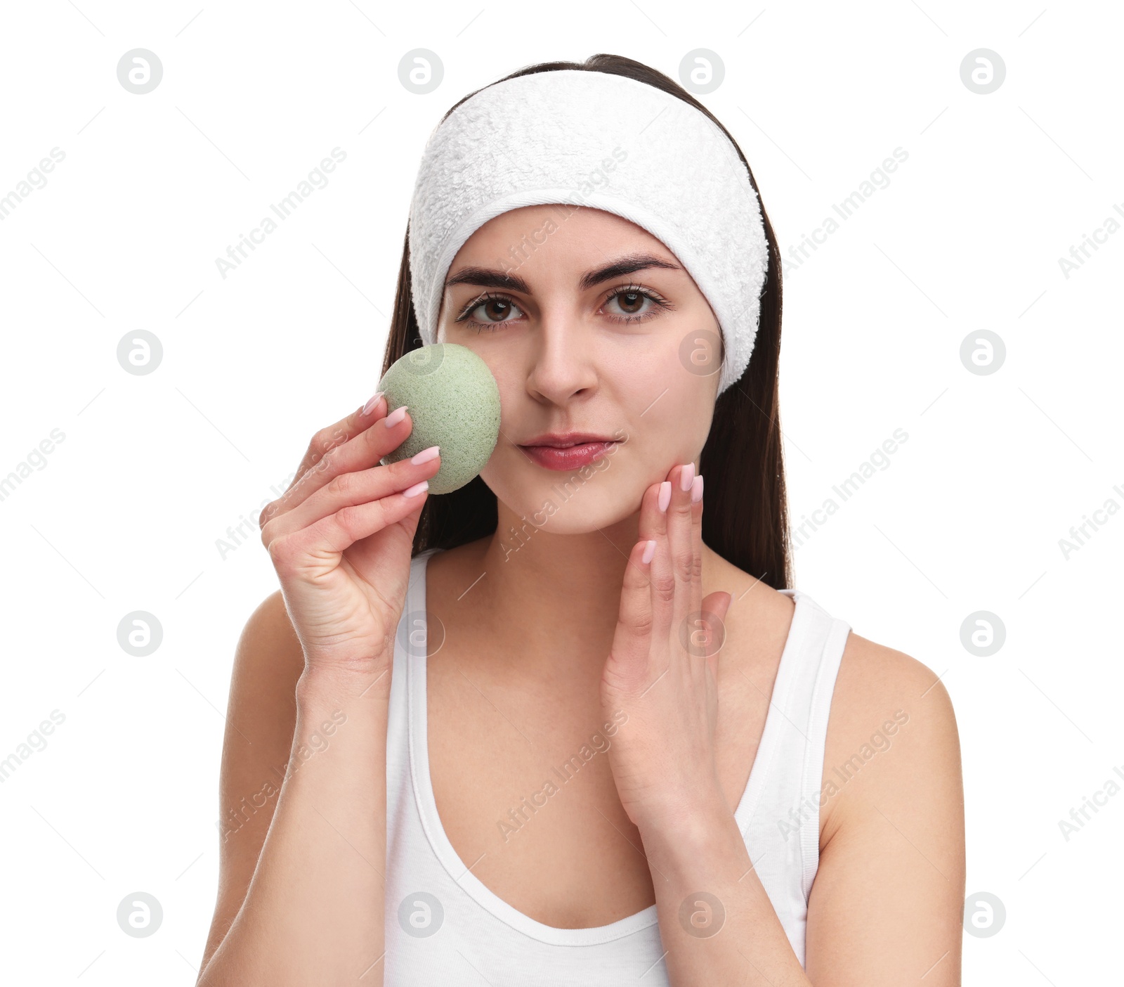 Photo of Young woman with headband washing her face using sponge on white background