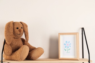 Photo of Shelf with toy rabbit and picture in child room. Space for text