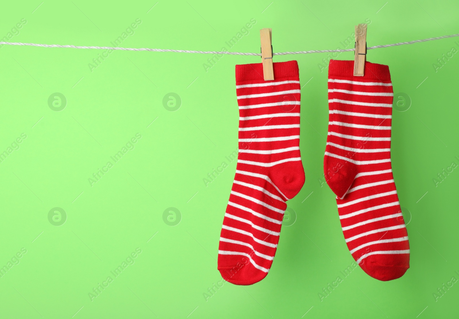 Photo of Cute child socks on laundry line against color background. Space for text