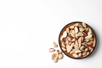 Photo of Wooden bowl with Brazil nuts and space for text on white background, top view
