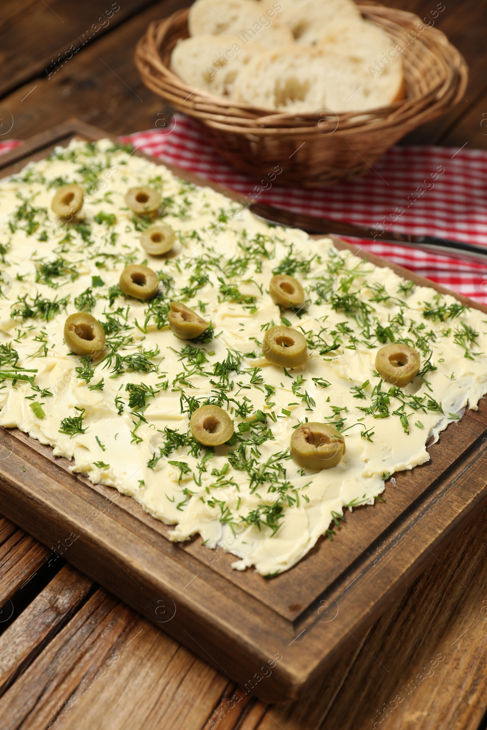 Photo of Fresh butter board with cut olives and dill on wooden table, closeup