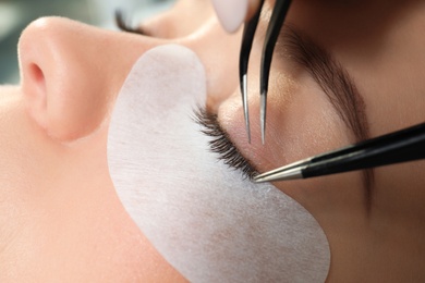 Photo of Young woman undergoing eyelash extension procedure, closeup