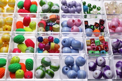 Photo of Plastic organizer with different beads as background, closeup