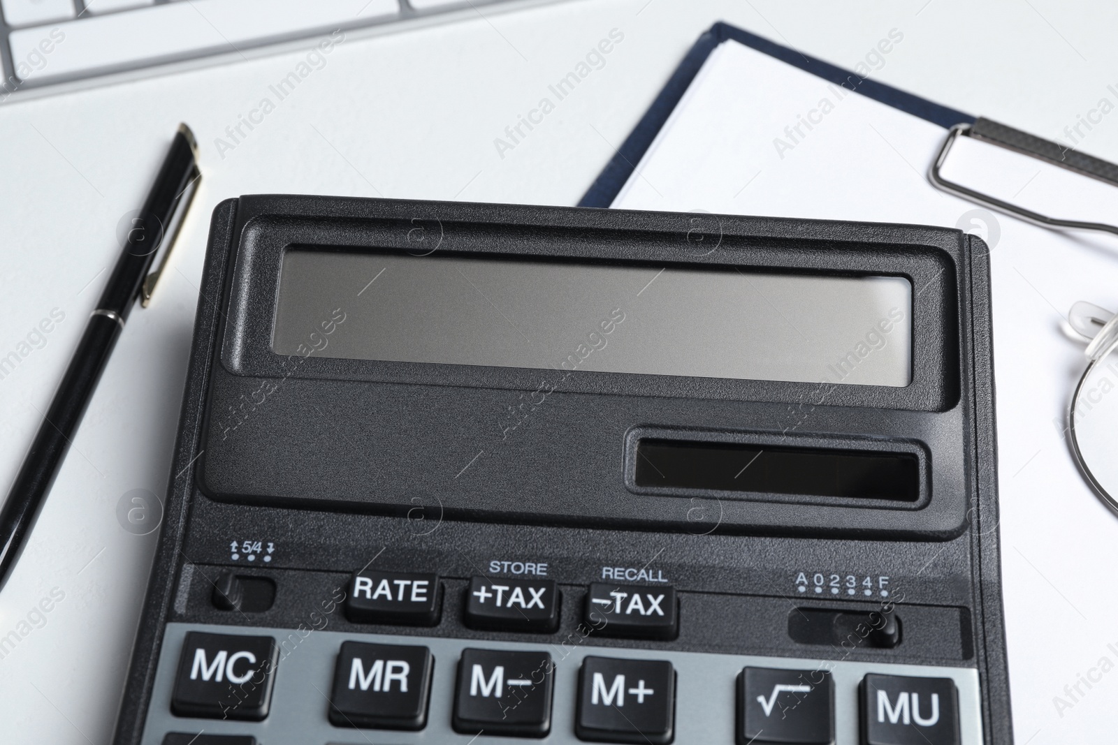 Photo of Calculator, clipboard and glasses on white background, closeup. Tax accounting