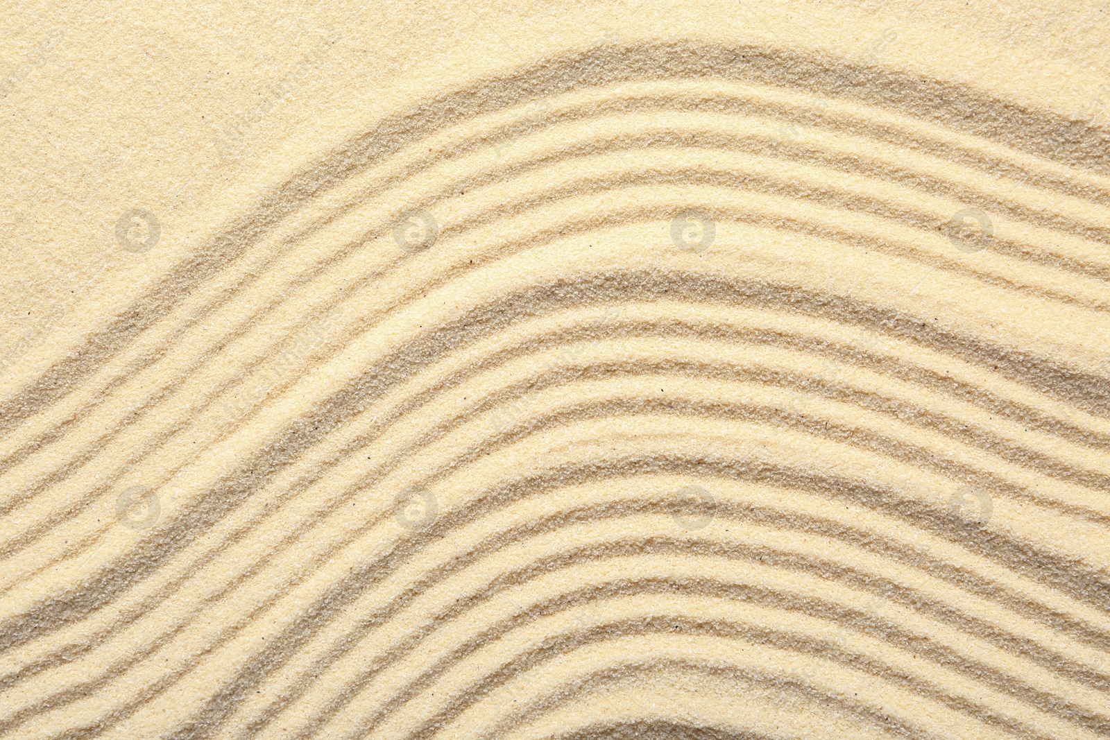 Photo of Zen rock garden. Wave pattern on beige sand, top view