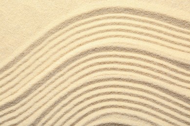 Photo of Zen rock garden. Wave pattern on beige sand, top view