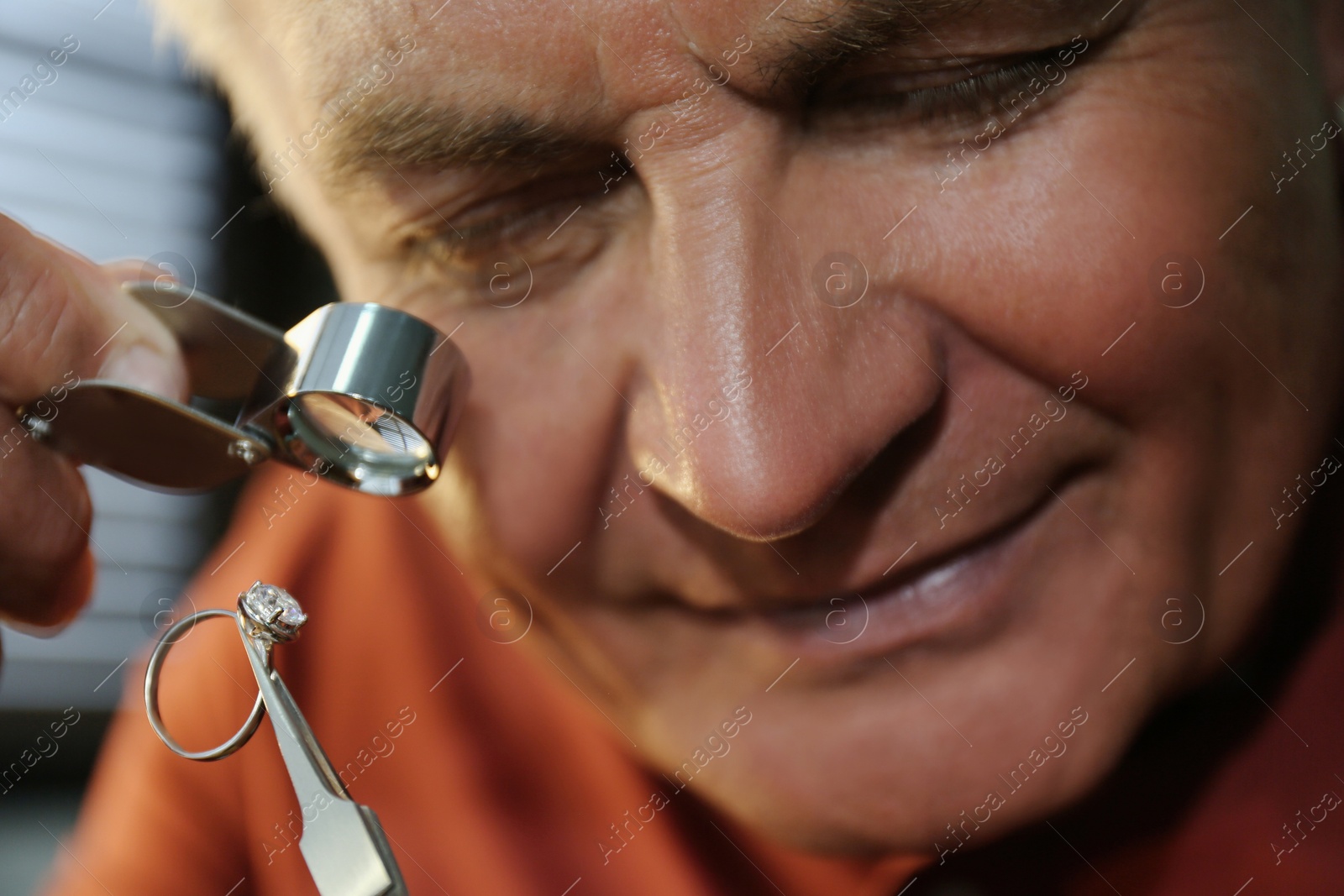 Photo of Professional jeweler evaluating beautiful ring in workshop, closeup