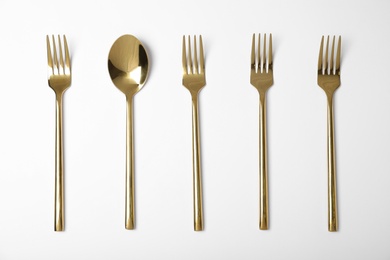 Set of new gold cutlery on white background, top view