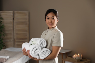 Photo of Portrait of young Asian masseur with towels in spa salon