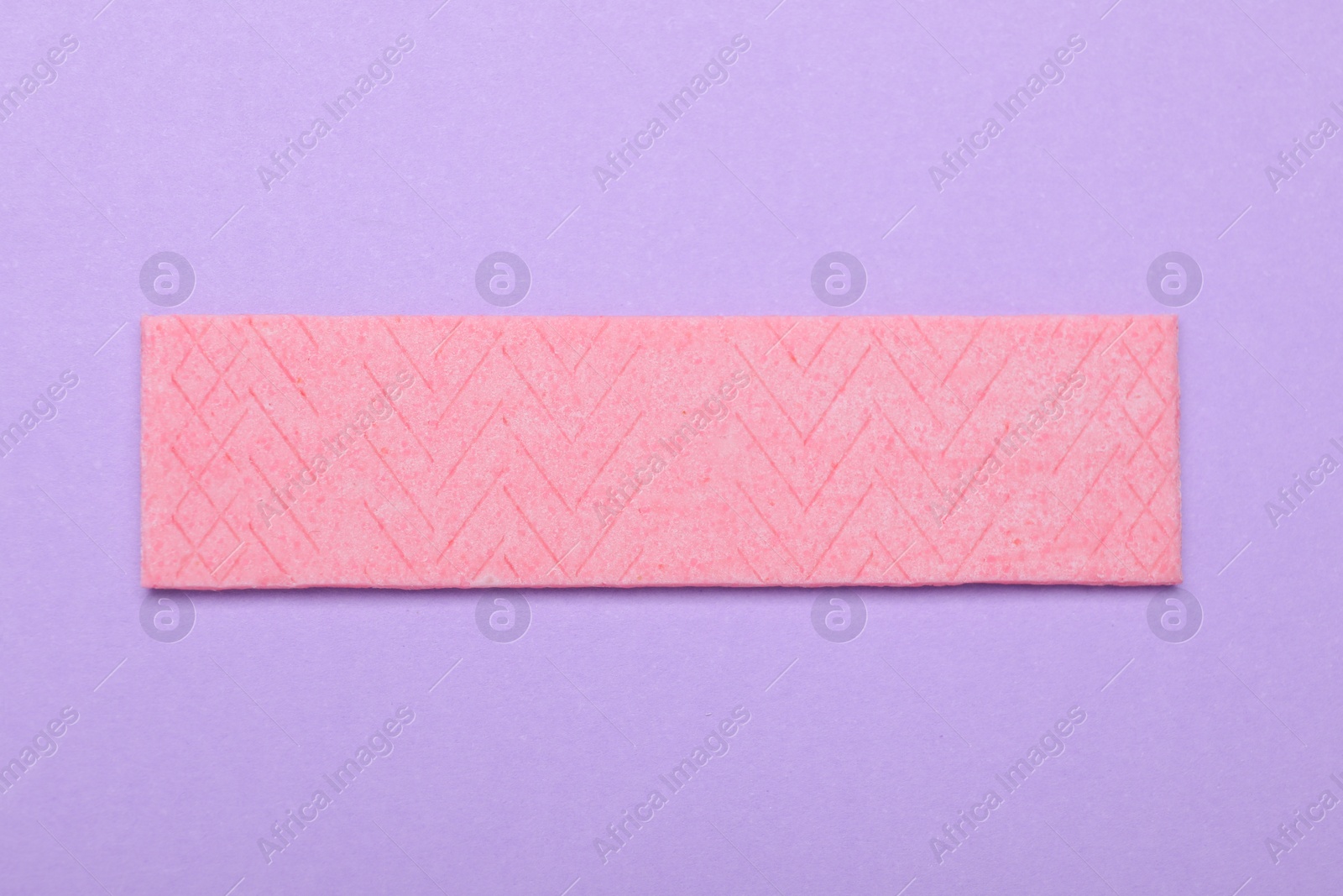 Photo of One stick of tasty chewing gum on violet background, top view