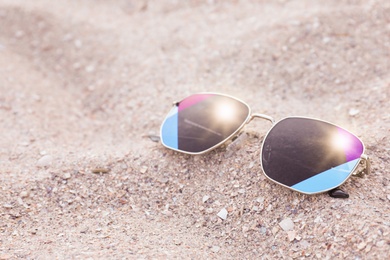 Photo of Stylish sunglasses on sandy beach. Space for text