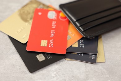 Photo of Many different credit cards and leather wallet on grey table, closeup