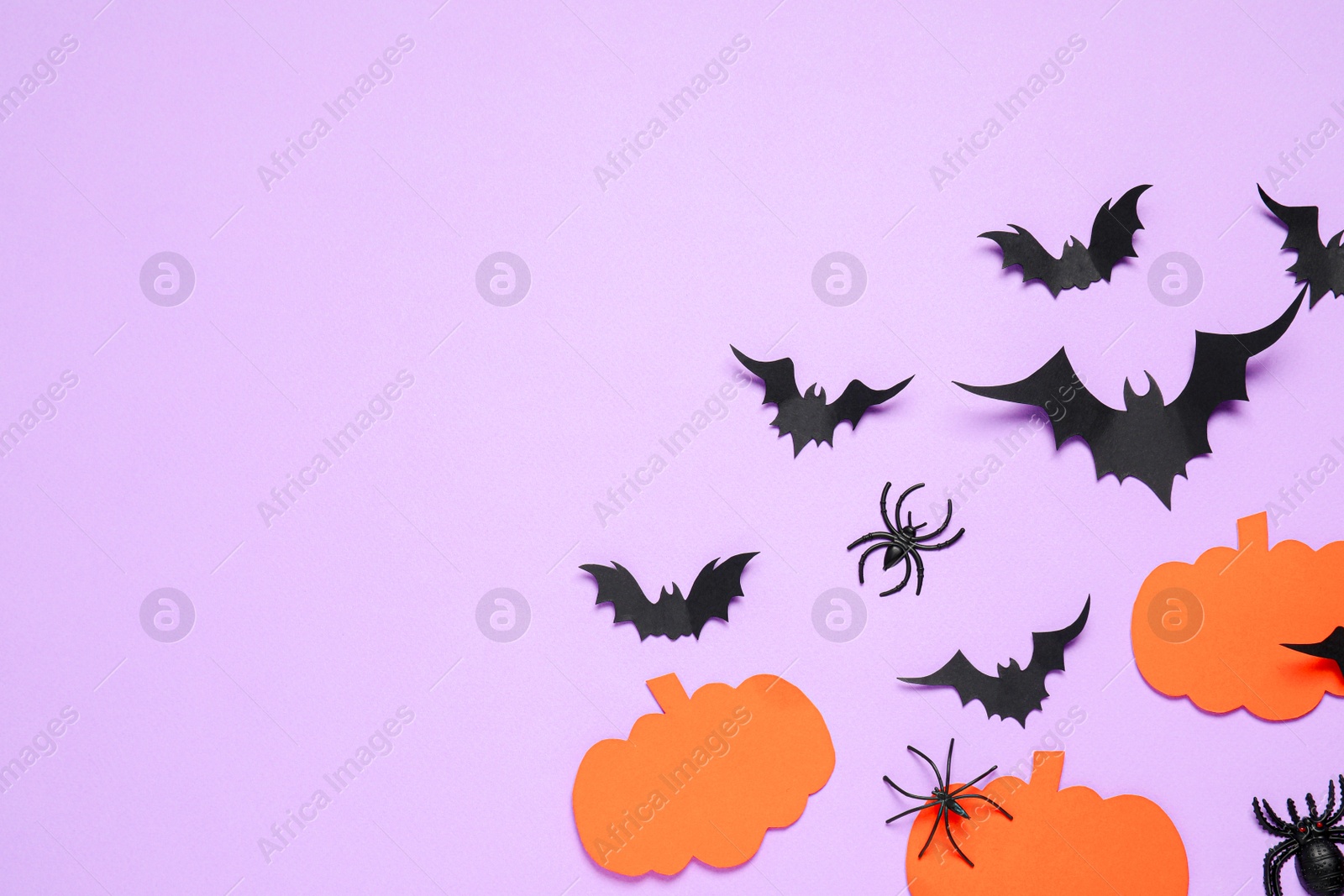 Photo of Flat lay composition with paper bats, spiders and pumpkins on light violet background, space for text. Halloween decor