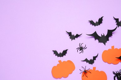 Flat lay composition with paper bats, spiders and pumpkins on light violet background, space for text. Halloween decor