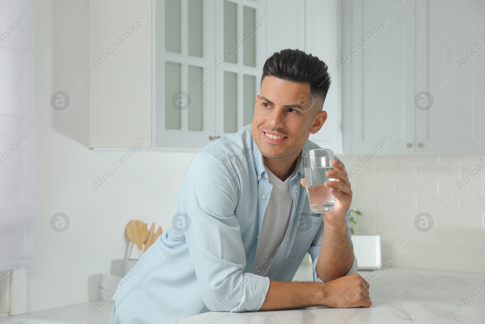 Photo of Man with glass of tap water in kitchen