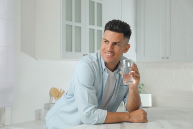 Photo of Man with glass of tap water in kitchen
