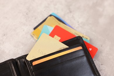 Photo of Many different credit cards and leather wallet on grey table, closeup