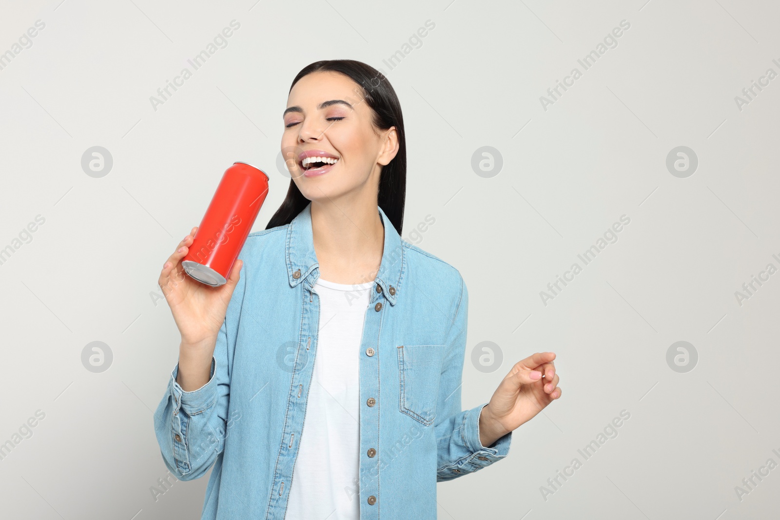 Photo of Beautiful happy woman holding red beverage can on light grey background. Space for text