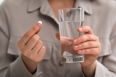 Photo of Woman holding antidepressant pill and glass of water, closeup