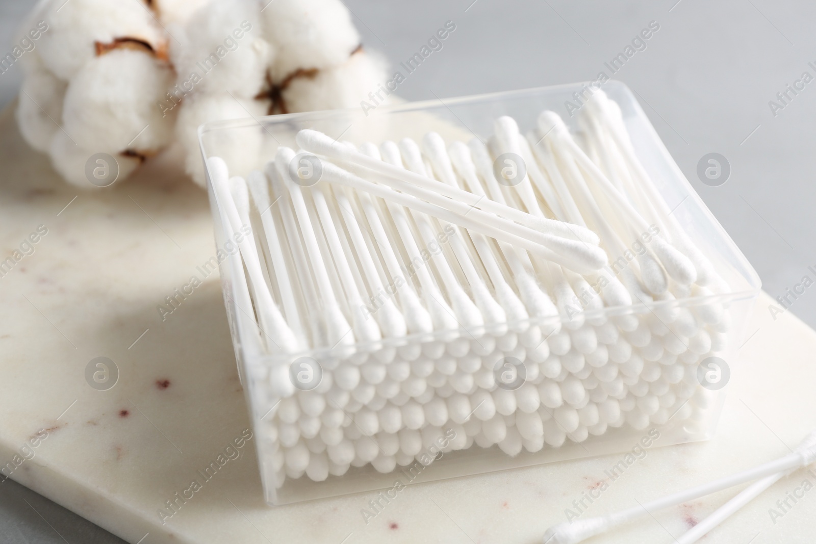 Photo of Plastic container with cotton swabs on stone board, closeup