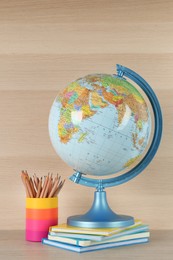 Photo of Globe, books and school supplies on wooden table. Geography lesson