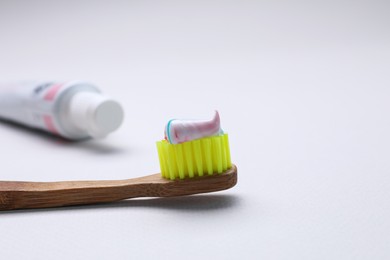 Photo of Brush with toothpaste and tube on white background, closeup