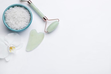 Photo of Gua sha stone, face roller, bath salt and orchid flower on white background, flat lay. Space for text