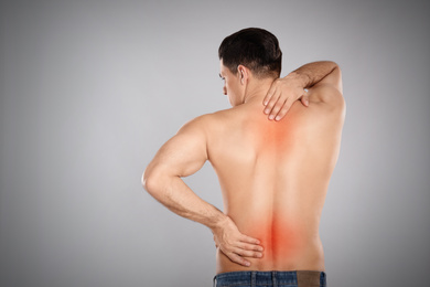 Man suffering from pain in lower back on light grey background