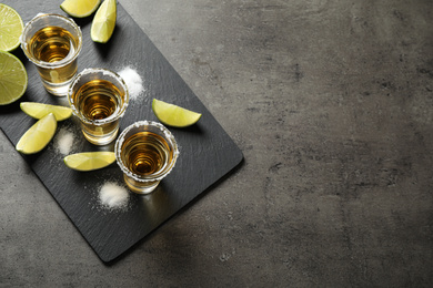 Photo of Mexican Tequila shots with salt and lime on grey table, above view. Space for text