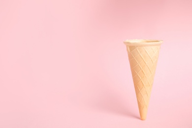 Photo of Empty wafer ice cream cone on pink background. Space for text