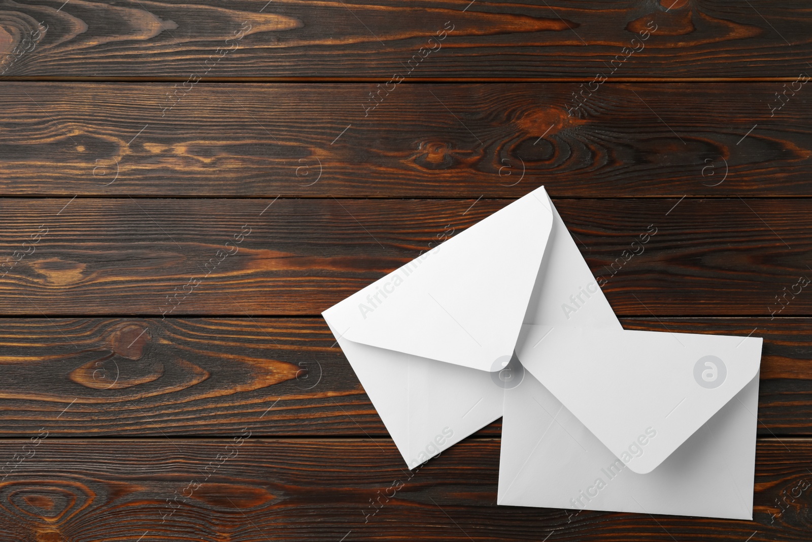 Photo of White paper envelopes on wooden background, flat lay. Space for text