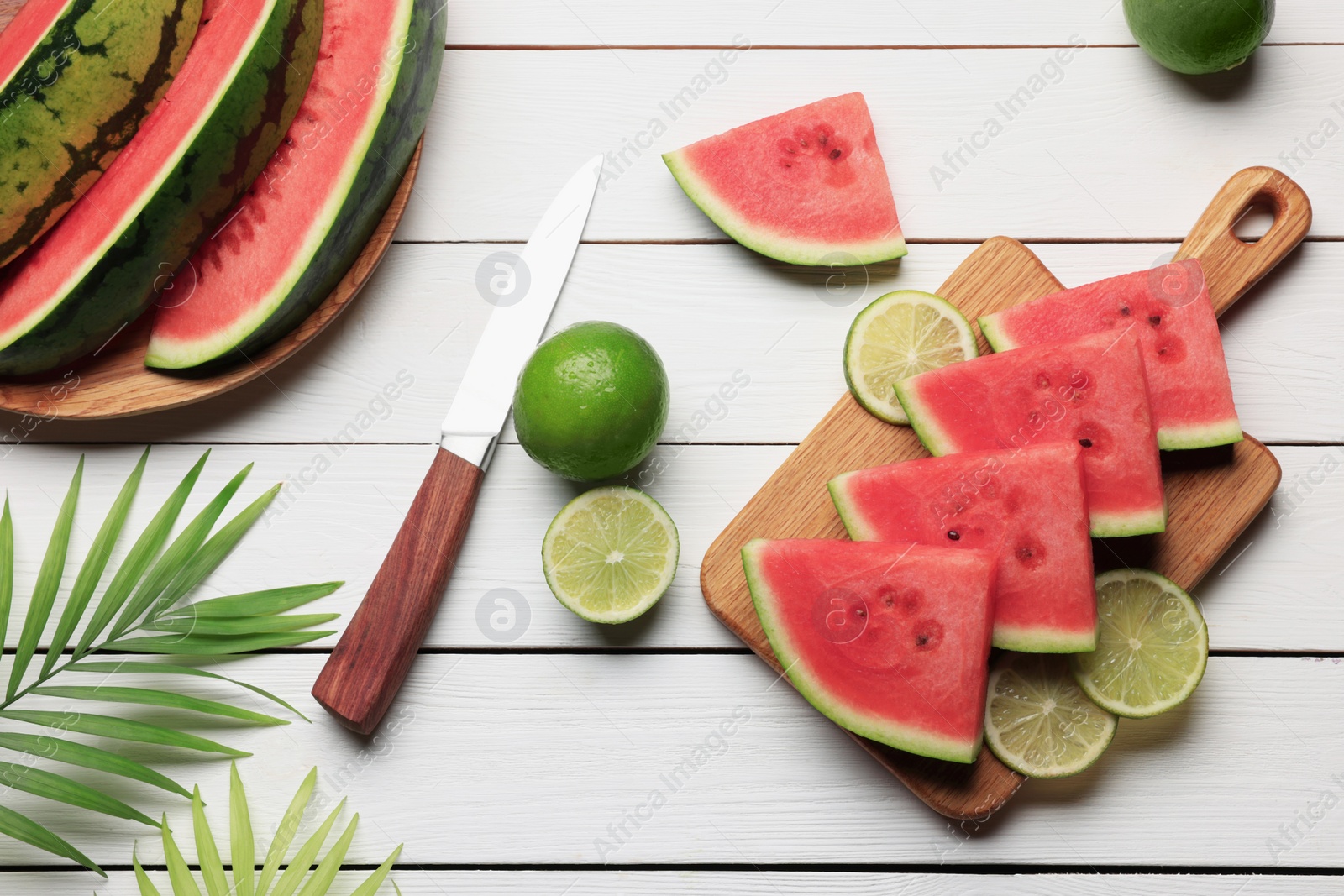 Photo of Tasty sliced watermelon and limes on white wooden table, flat lay