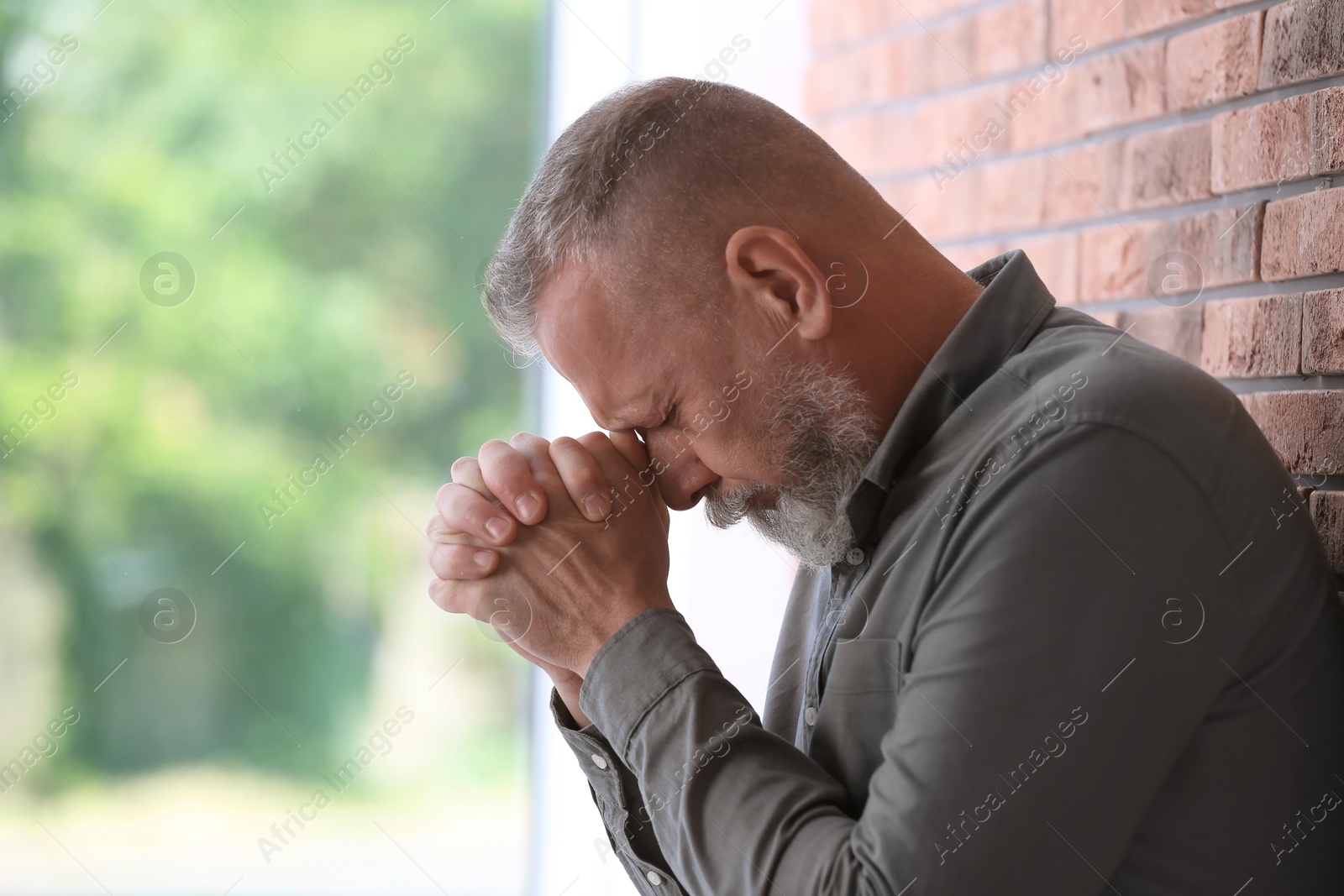 Photo of Senior man in state of depression near brick wall