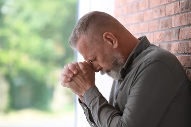 Photo of Senior man in state of depression near brick wall