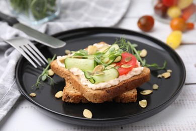 Photo of Tasty vegan sandwich with cucumber, tomato and pumpkin seeds on white wooden table, closeup